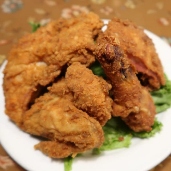 A white plate piled high with golden-brown fried chicken pieces on a bed of green lettuce.